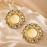 Gold earrings with gemstones on a beige fabric background