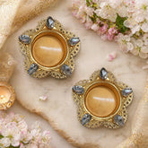 Decorative gold candle holders with gemstones on a marble surface with flowers and candles.