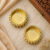 Pair of gold earrings with gemstones on a beige fabric background