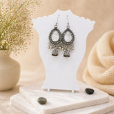 Pair of silver earrings on a white stand with a soft beige background