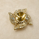 Decorative gold candle holder with gemstone accents on a beige background