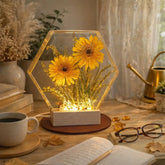 Decorative light box with yellow flowers on a table with a cup of coffee and glasses.