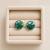 Handmade emerald green crystal resin stud earrings displayed in a beige velvet jewellery tray with glossy transparent dome finish