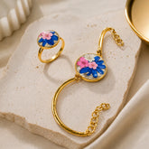 Gold ring and bracelet with floral design on a stone surface
