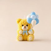 Yellow teddy bear candle with balloons on a beige background