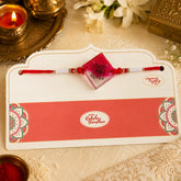 Rakhi with a card on a decorative surface with candles and flowers