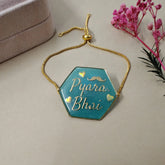 Hexagonal blue pendant with gold chain on a light surface with pink flowers in the background