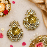 Decorative gold earrings with gemstones on a light background with flowers and candles.
