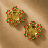 Pair of gold earrings with green and pink gemstones on a beige background