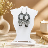 Oxidised silver mirror jhumka earrings displayed on white jewellery stand with intricate ethnic design