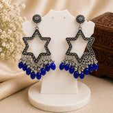 Star-shaped earrings with blue beads on a white stand with a neutral background