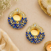 Pair of gold and blue decorative earrings on a beige background with flowers.