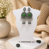 Pair of earrings on a white stand with a soft beige background