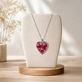 Necklace with a pink heart-shaped pendant on a white bust against a neutral background