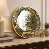 Decorative round mirror with gold frame on a shelf in a home setting