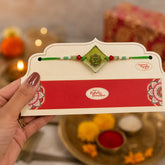 Hand holding a Rakhi with a decorative card against a blurred festive background