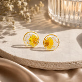 Yellow flower earrings on a stone surface with a soft background