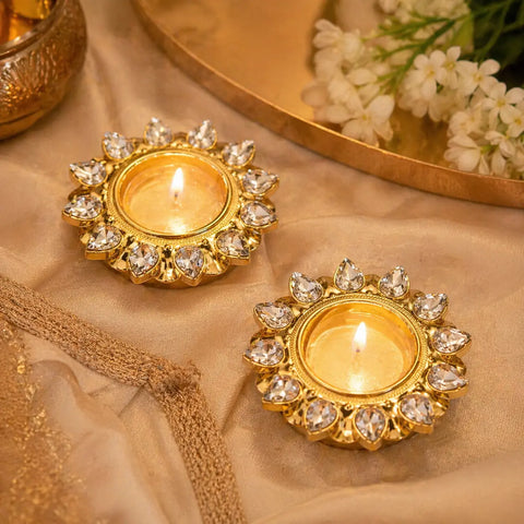 Decorative gold candle holders with crystals on a beige fabric background.