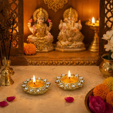 Gold finish 12 stone T-light candle holders placed in pooja mandir with lit candles, festive Diwali home decor setup with idols and flowers