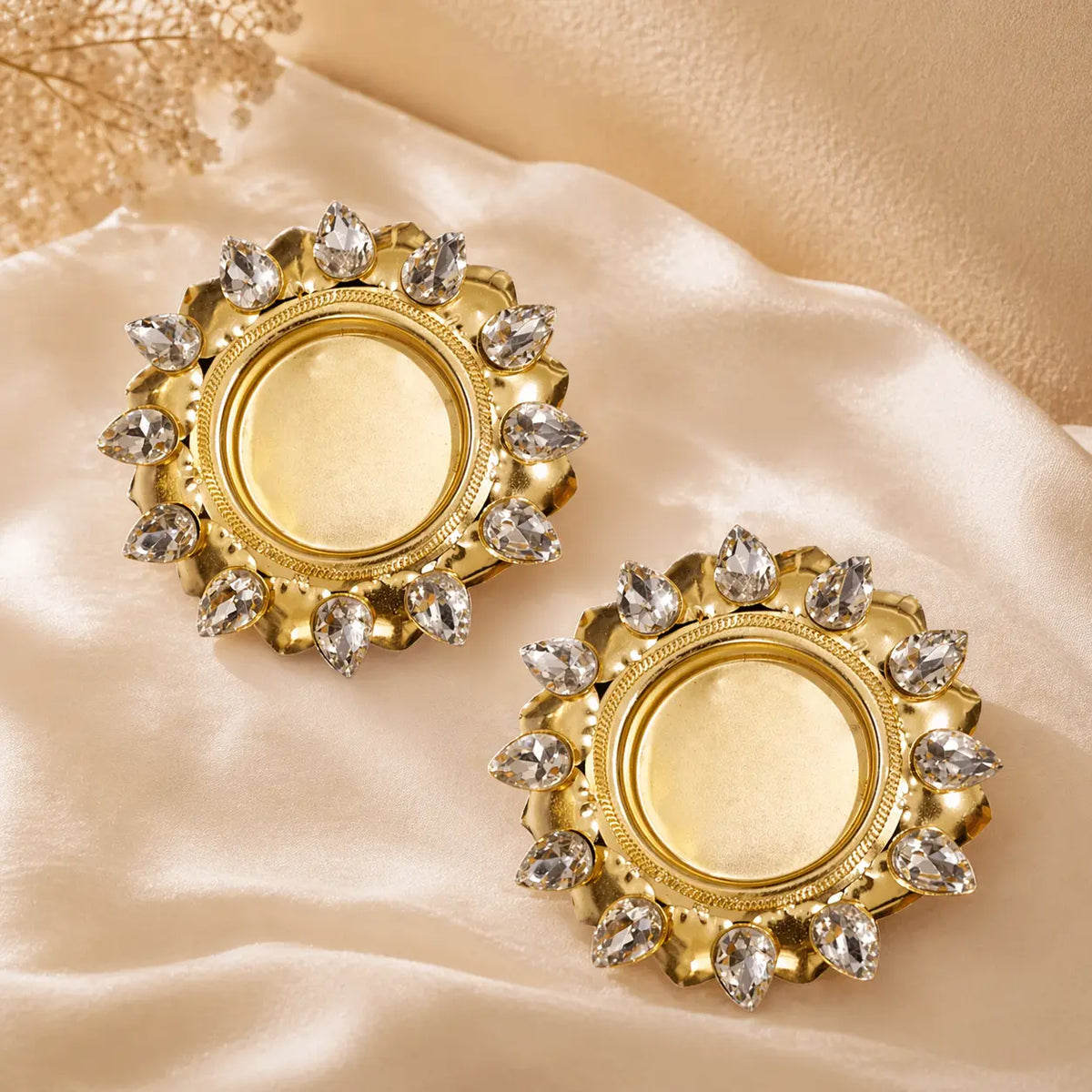 Gold earrings with gemstones on a beige fabric background