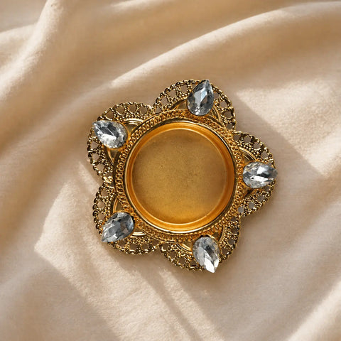 Decorative gold brooch with gemstones on a beige fabric background