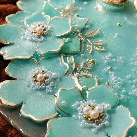Decorative cookies with turquoise icing, gold accents, and pearl-like centers.