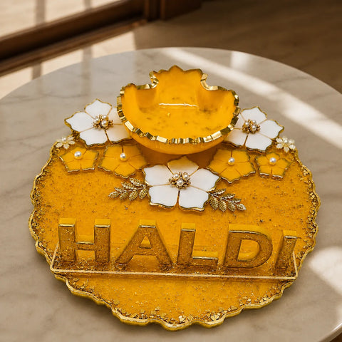 Decorative yellow and gold item with 'HALDI' text on a marble surface