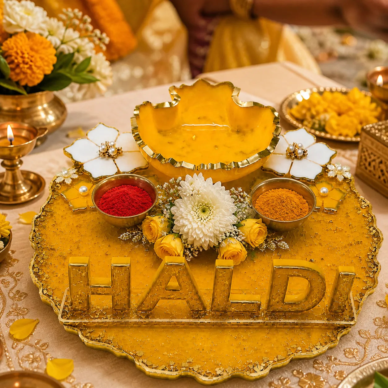 Decorative setup with 'Haldi' on a table, featuring flowers and colored powders.