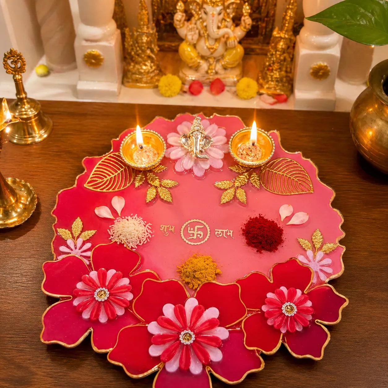 resin pooja thali in pink red with gold accents used with diya and kumkum for festive pooja setup