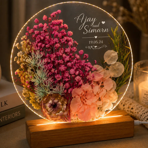 Decorative lamp with dried flowers and engraved names on a wooden base