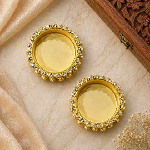 Pair of gold earrings with gemstones on a beige fabric background