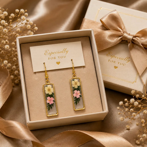 Floral resin rectangle drop earrings with white and pink dried flowers displayed in a premium gift box setup with satin ribbon and elegant luxury background