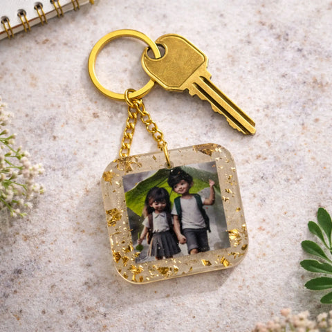 Keychain with a photo of two children on a textured surface with a key and flowers.