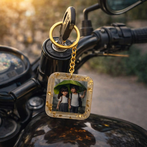 Keychain with a photo of two children holding an umbrella on a motorcycle handlebar.