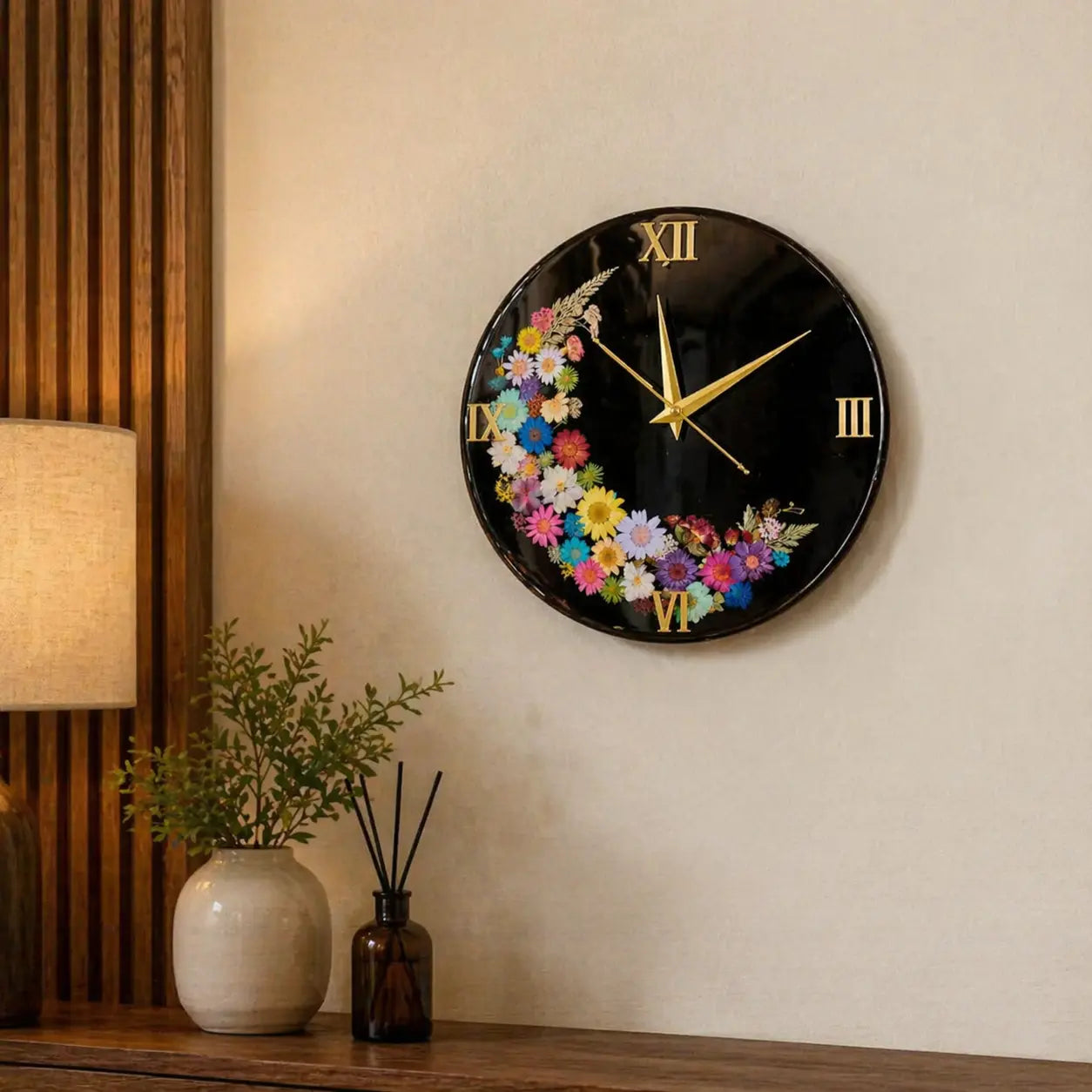 Decorative wall clock with floral design on a wall with a lamp and plant in the background