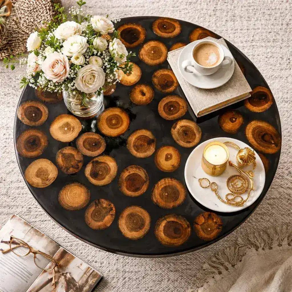 Round wooden coffee table with decorative items including a flower arrangement, books, and a candle.