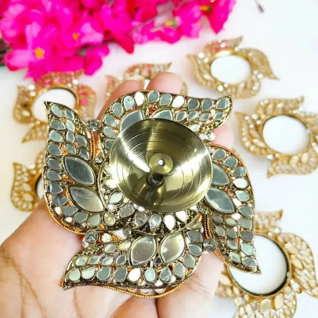 Decorative gold and green lamp held by a hand with flowers in the background