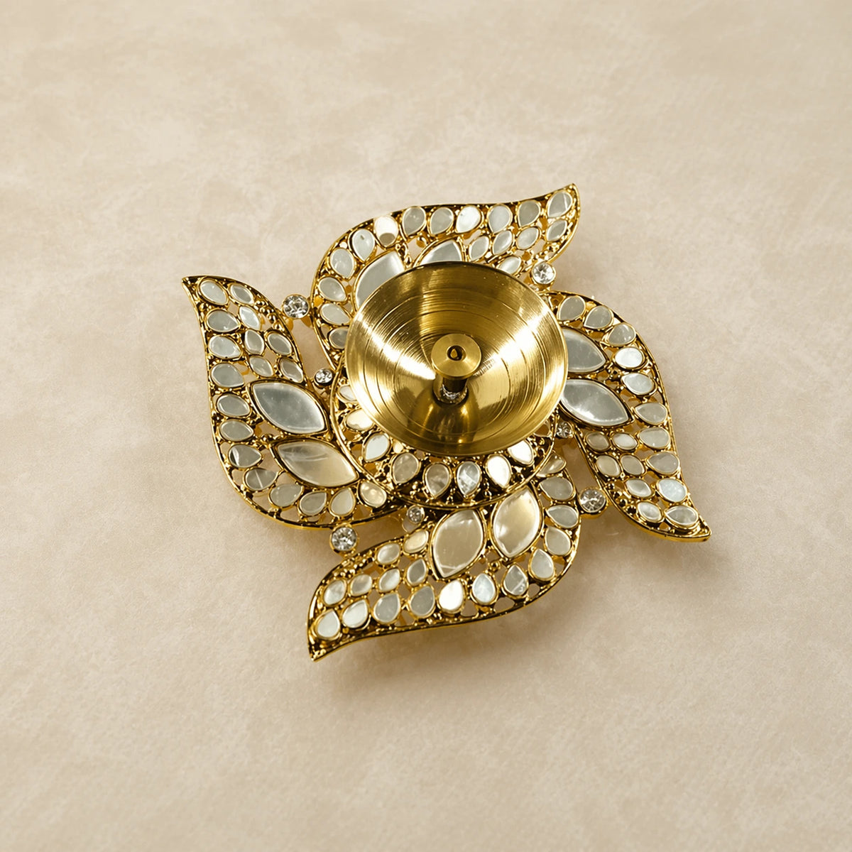 Decorative gold candle holder with gemstone accents on a beige background