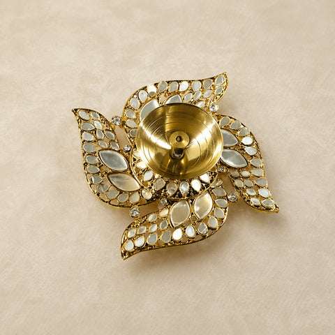 Decorative gold candle holder with gemstone accents on a beige background