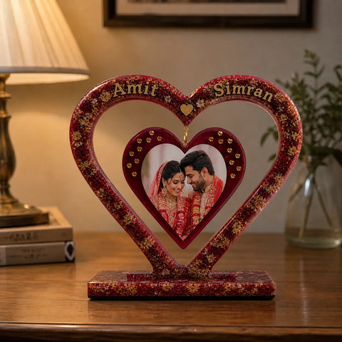 Decorative heart-shaped photo frame with a couple's photo inside, placed on a wooden surface.