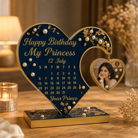 Heart-shaped birthday decoration with calendar and photo frame on a wooden table.