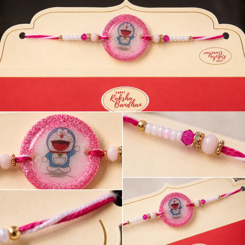 Cartoon-themed rakhi with decorative beads on a branded card, featuring 'Happy Raksha Bandhan' text.
