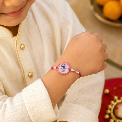 Child wearing a bracelet with a decorative charm, dressed in a cream outfit.