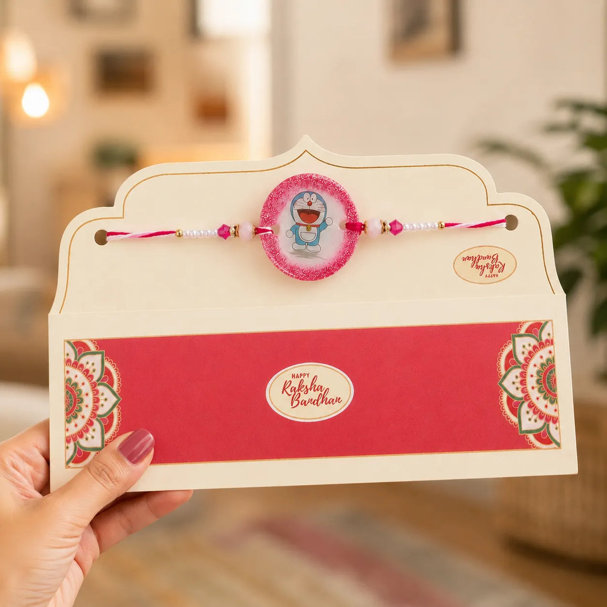 Rakhi with a card held by a hand, blurred indoor background