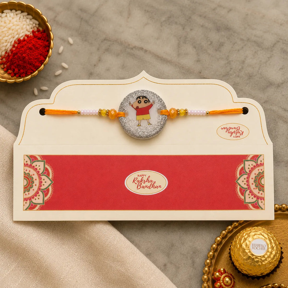 Rakhi with a card on a textured surface with decorative items around