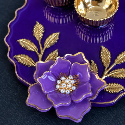 Purple flower-shaped jewelry dish with gold accents on a dark surface