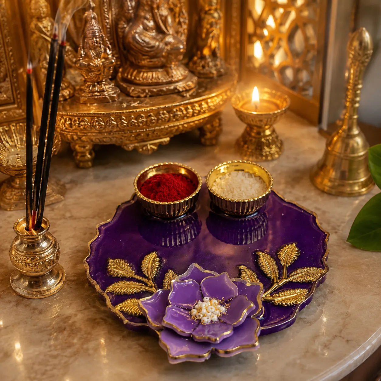 Decorative setting with gold religious statue, purple tray with red and white powders, and incense sticks.