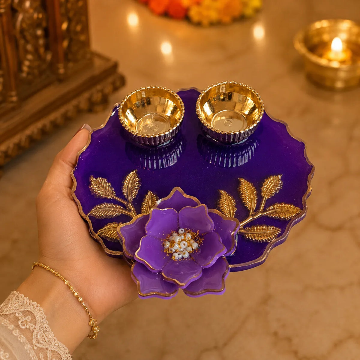 Decorative purple plate with gold floral design held by a hand, with a blurred background of lights and objects.