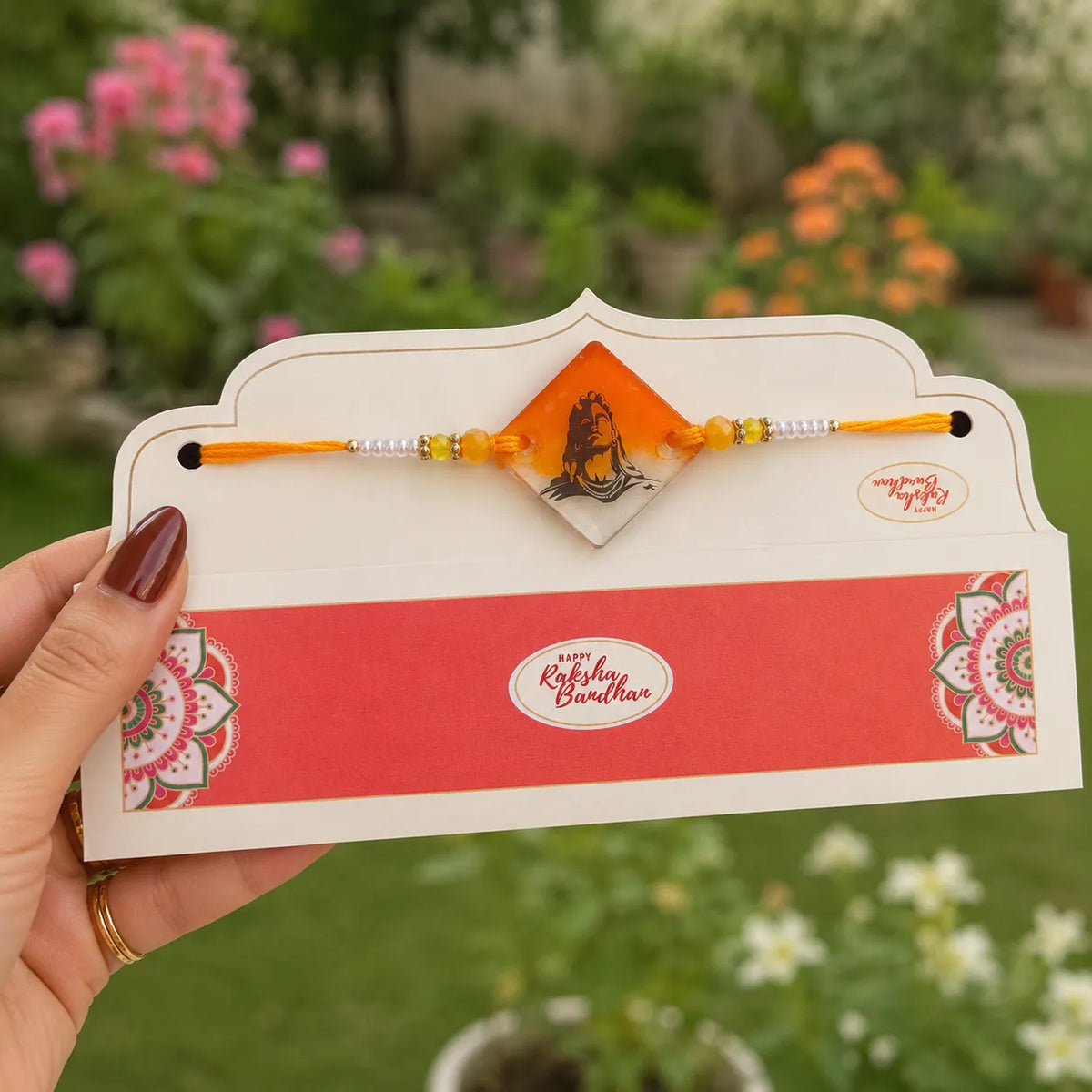 Rakhi with a decorative card held by a hand against a garden background