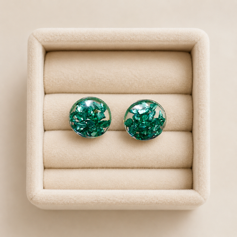 Handmade emerald green crystal resin stud earrings displayed in a beige velvet jewellery tray with glossy transparent dome finish